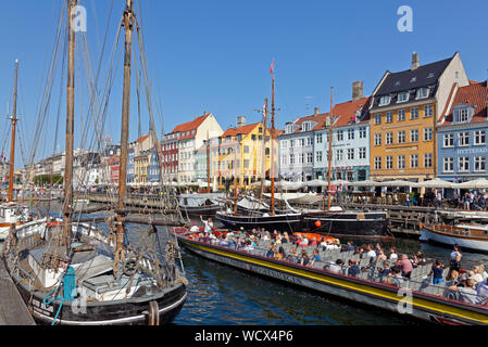 Canal Cruise Boot vorbei an alten historischen Segelschiffe und und den farbenfrohen alten Häuser auf dem Weg zurück durch Nyhavn Kanal in Kopenhagen, Dänemark. Stockfoto