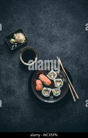 Sushi und Sashimi auf Schwarz japanische Platte mit Holz hacken, in eine Schüssel geben und Sojasauce, Ingwer und Wasabi. Stockfoto