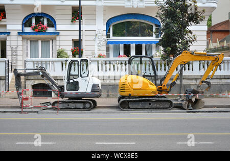 Kleine weiße und gelbe Bagger auf der Straße in Frankreich Stockfoto