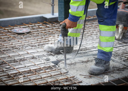 Worker ist bohren Beton mit multifunktionalen hammer Breaker, Detail der Bau Szene. Stockfoto