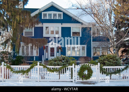 Blaues Haus mit Weihnachten Kranz auf Zaun Tor im Winter Stockfoto