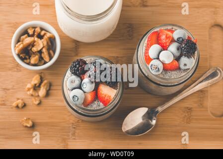 Overhead Nahaufnahme Schuss von gemischten Beeren in einem Glas mit Eis und griechische Nüsse auf der Seite Stockfoto