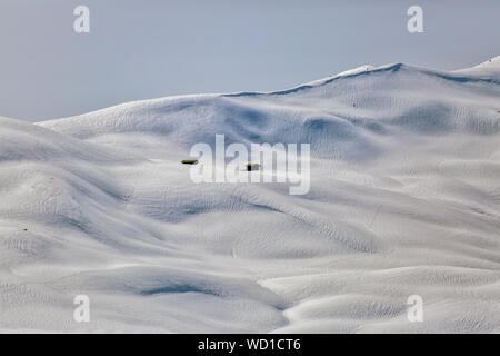 An einem sonnigen Tag am Frühlingsanfang wird ein riesiges Volumen an Schneepulverlinien zum Skifahren und Snowboarden von einem Kamm bei Megeve/Chamonix der französischen Alpen erreicht. Stockfoto