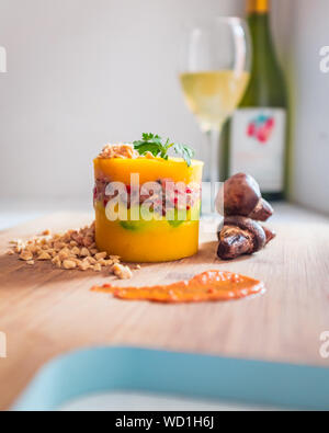 Peruanische Gericht, Causa Limeña mit gerösteten Champignons, von einem Glas Wein Stockfoto