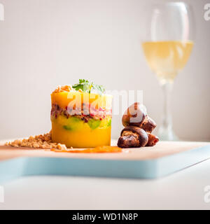 Peruanische Gericht, Causa Limeña mit gerösteten Champignons, von einem Glas Wein Stockfoto