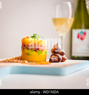 Peruanische Gericht, Causa Limeña mit gerösteten Champignons, von einem Glas Wein Stockfoto