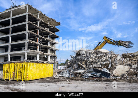 Gebäude Haus Abbruchbaustelle Bagger mit hydraulischen crasher Maschine und gelbe Container. Stockfoto