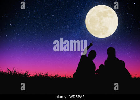 Glückliche Familie sitzt auf einem Hügel und beobachtete den Mond und Stern. Feiern in den Herbst Festival Stockfoto