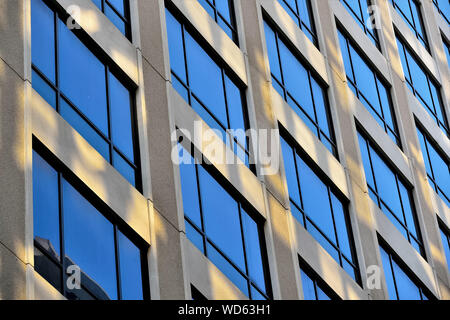 Perspektivische Ansicht des modernen Fassade des Bürogebäudes mit geometrischen Mustern in Beton und Glas mit Abendsonne und blauen Tönen Stockfoto