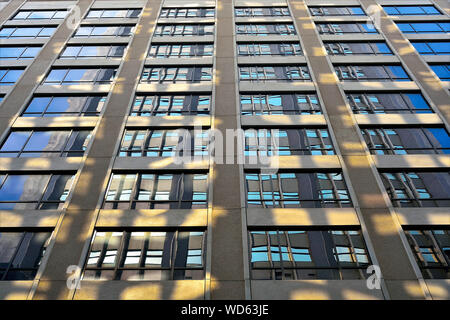 Perspektivische Ansicht des modernen Fassade des Bürogebäudes mit geometrischen Mustern in Beton und Glas mit Abendsonne und blauen Tönen Stockfoto