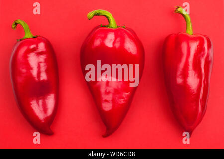 Drei rote Paprika auf rotem Hintergrund Top View close up Stockfoto