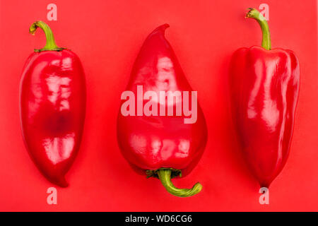 Drei rote Paprika auf rotem Hintergrund Top View close up Stockfoto
