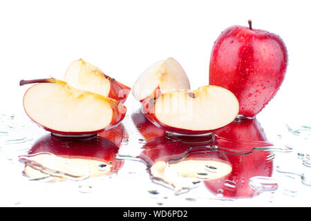 Ganzes Red Apple und Apple auf Viertel auf weißen Hintergrund mit Wassertropfen und Reflexion geschnitten isoliert Nahaufnahme Stockfoto