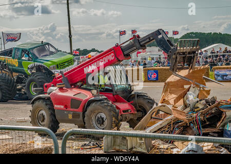 Ein Gabelstapler neu anordnen die Überreste eines zerstörten Caravan während der Sumpf Sache Monster Truck in der Nähe geparkt ist. Während t erfasst Stockfoto