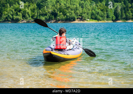 Junge aktive Frau Kajakfahren in aufblasbare Kajak fahren auf dem See, in Lokve Gorski kotar, Kroatien. Abenteuerliche Erfahrung an einem schönen sonnigen Tag. Stockfoto