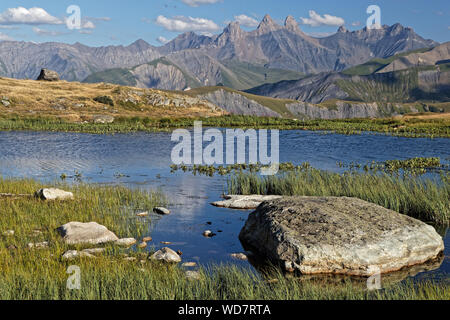 Ufer des Guichard See auf dem Col de la Croix de Fer, mit Aiguilles d'Arves im Hintergrund Stockfoto