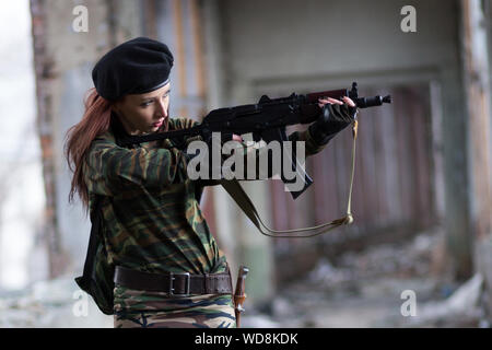 Soldat Mädchen mit Waffen in der Tarnung Uniform in einem zerstörten Gebäude. Der Begriff der Dienstleistung in der Armee Stockfoto