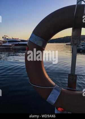 Vertikale Aufnahme eines Rettungsschwimmenrads auf dem Hintergrund Der weißen Yacht auf dem Körper des Wassers Stockfoto