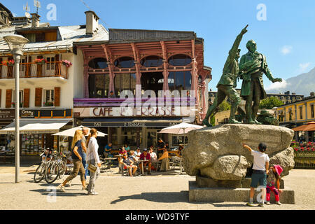 Blick auf das historische Zentrum von Chamonix-Mont-Blanc mit der Bronzestatue von Saussure und Balmat und Café im Freien mit Touristen, Alpen, Frankreich Stockfoto