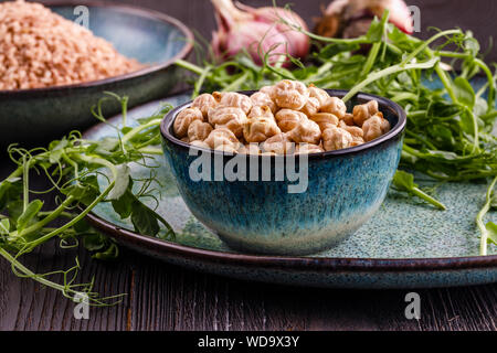 Rohe getrocknete Kichererbsen in Schale mit rohen grünen Kichererbse Pflanzen auf hölzernen Tisch Stockfoto