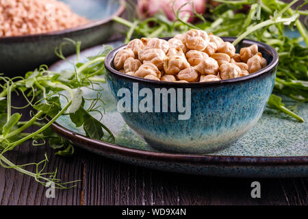 Rohe getrocknete Kichererbsen in Schale mit rohen grünen Kichererbse Pflanzen auf hölzernen Tisch Stockfoto