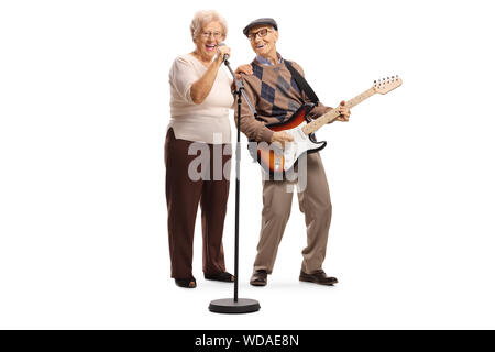 In voller Länge Porträt einer älteren Frau singen auf ein Mikrofon und ein älterer Herr spielt eine Gitarre auf weißem Hintergrund Stockfoto