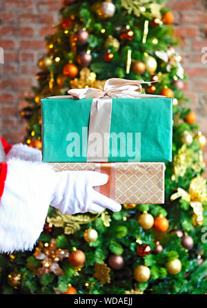 Santa Claus insgeheim anbringen Geschenkboxen durch den Weihnachtsbaum. Weihnachten Stockfoto