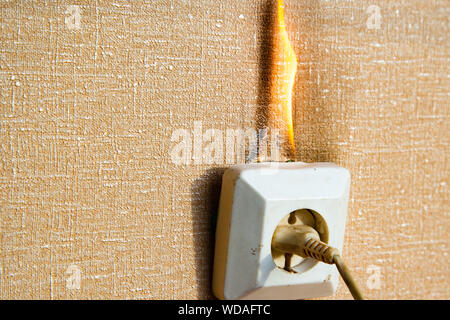 Brennende elektrische Verkabelung und aus der Steckdose. Fehlerhafte Verdrahtung verursacht Brände. Arme alte Verkabelung verursacht einen Brand in der Steckdose. Stockfoto