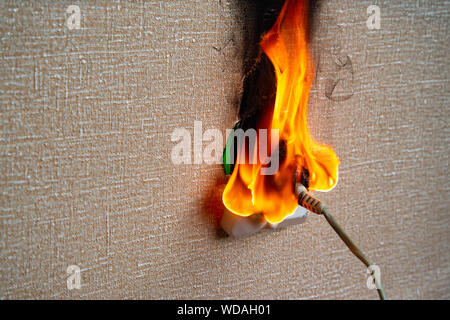 Brennende elektrische Verkabelung und aus der Steckdose. Fehlerhafte Verdrahtung verursacht Brände. Arme alte Verkabelung verursacht einen Brand in der Steckdose. Stockfoto