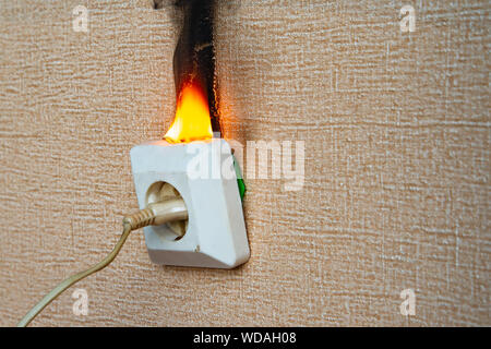 Brennende elektrische Verkabelung und aus der Steckdose. Fehlerhafte Verdrahtung verursacht Brände. Arme alte Verkabelung verursacht einen Brand in der Steckdose. Stockfoto