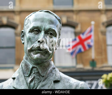 Eine Statue von Edward Elgar in der Mitte der Great Malvern, Worcestershire, mit einer britischen Flagge im Hintergrund. Stockfoto