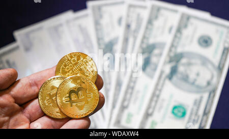 Bitcoins auf dem Hintergrund der Dollar. olden Bitcoins. Neue virtuelle Geld. symbolische Münzen von bitcoin auf Banknoten von einhundert Dollar. Austausch Stockfoto