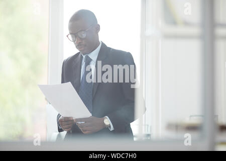 Schweren afrikanischen Manager in formale Abnutzung und Prüfung der Vertrag im Büro Stockfoto