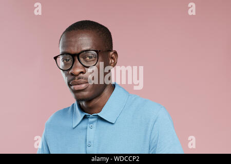 Portrait der Afrikanischen hübscher Kerl in Brillen und in Freizeitkleidung auf Kamera über rosa Hintergrund Stockfoto