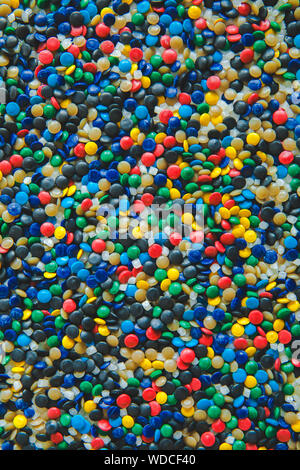 Industrielle bunte Polymere Farbstoff. Kunststoffgranulat. Farbmittel für Kunststoffe. Pigment in der Kunststoff Polyethylen Granulat Hintergrund Textur. Stockfoto