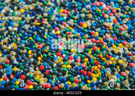 Industrielle bunte Polymere Farbstoff. Kunststoffgranulat. Farbmittel für Kunststoffe. Pigment in der Kunststoff Polyethylen Granulat Hintergrund Textur. Stockfoto