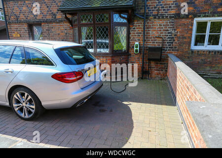Ein Mercedes C350 elektrische hybride Kombi elektrisch in der Fahrstraße durch ein Haus Ladestation, Staffordshire, England, UK geladen wird Stockfoto
