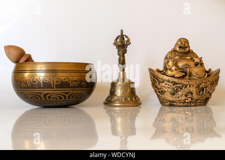 Klangschale, Figurine fröhliche Hotei und Golden Bell close-up, beruhigend und meditativ. Klangschale mit Sanskrit Gravur Pattern- und Holz- mals Stockfoto