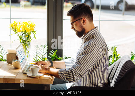 Stattliche ernster Mann auf seinem Laptop Stockfoto