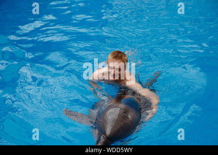 Glückliche Menschen schwimmen mit Delfin im Delphinarium Stockfoto