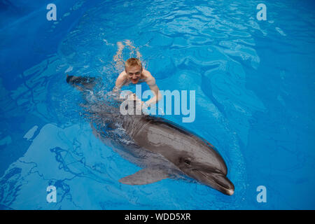 Glückliche Menschen schwimmen mit Delfin im Delphinarium Stockfoto