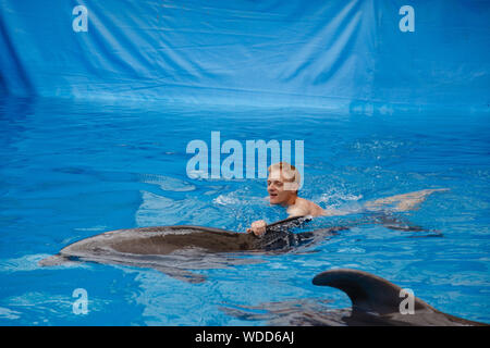 Glückliche Menschen schwimmen mit Delfin im Delphinarium Stockfoto