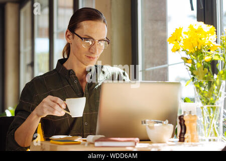 Angenehme langhaarigen Mann hält eine Schale mit Espresso Stockfoto