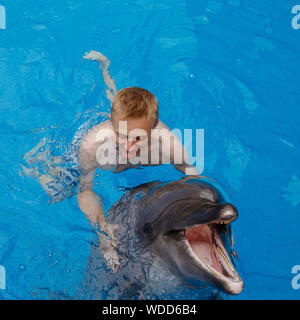 Glückliche Menschen schwimmen mit Delfin im Delphinarium Stockfoto