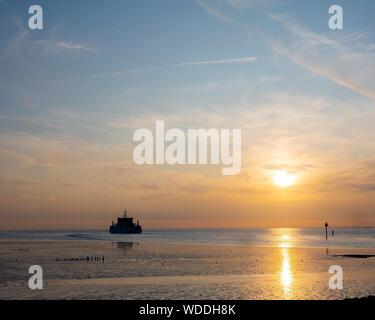 Fähre von Ameland kommt während der Sonnenuntergang am Hafen Holwerd in der niederländischen Provinz Friesland Stockfoto