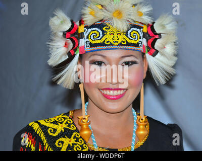 Malaiischen Dayak Tänzer trägt ihr traditionelles Sarawakian tribal Kostüm während einer Bornesischen Folk Festival und Lächeln für die Kamera. Stockfoto