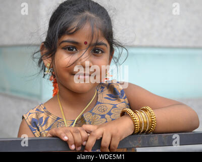 Wenig malaysischen Indisches Mädchen mit roten Bindi auf ihrer Stirn und goldene Armreifen um ihren linken Unterarm posiert für die Kamera. Stockfoto