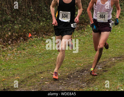 Zwei männliche Läufer Racing auf einem unbefestigten Pfad im Langlauf sind matschig, weil es regnet. Stockfoto