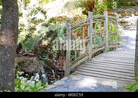 Ein altes rustikales Zaun über einen dünnen Strom in einem englischen Country Garden Stockfoto