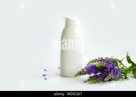 Weiß Plastische, kosmetische Flasche mit Spender in der Nähe von Lilac Blumen auf weißem Hintergrund. kosmetische Hilfsmittel für Hautpflege Stockfoto